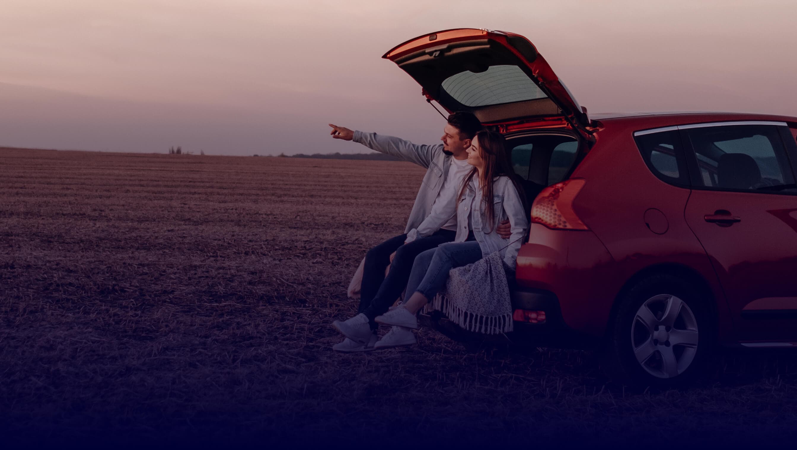 View from the inside of the car with a blurred view of the outside, overlooking some people standing in a field.