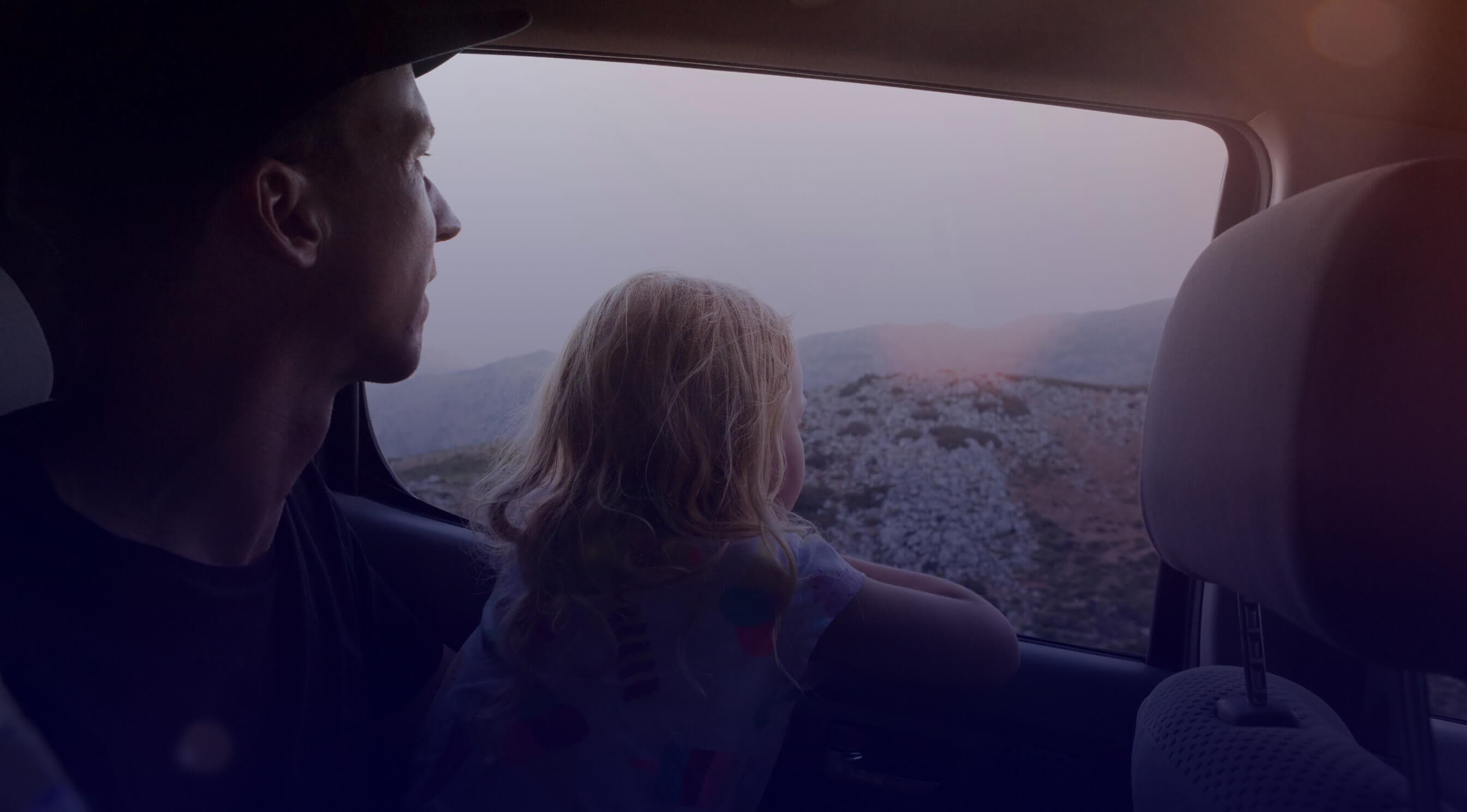 View from the inside of the car with a blurred view of the outside, overlooking some people standing in a field.