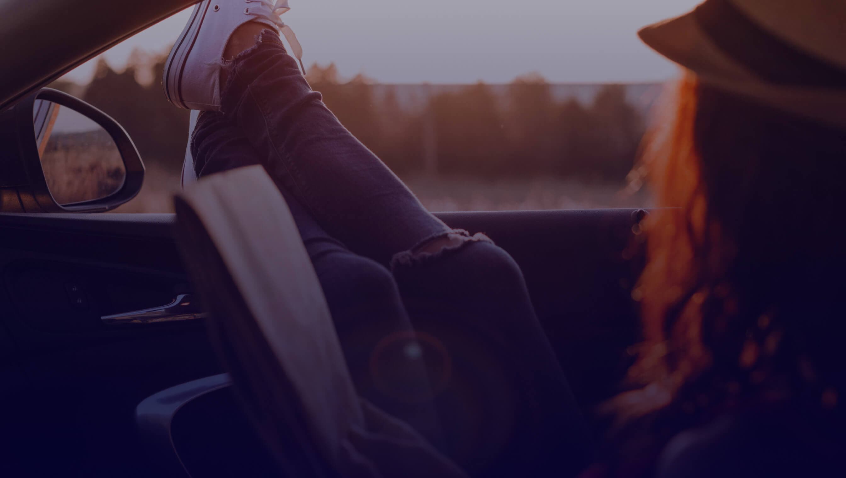 View from the inside of the car with a blurred view of the outside, overlooking some people standing in a field.