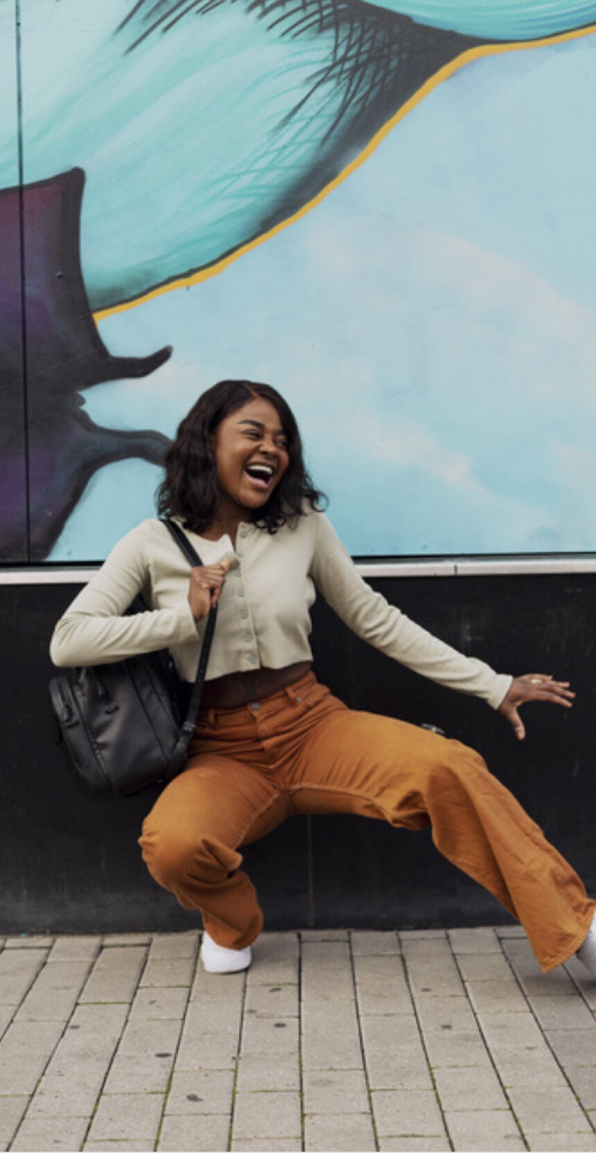 A girl dances in front of a wall and smiles.